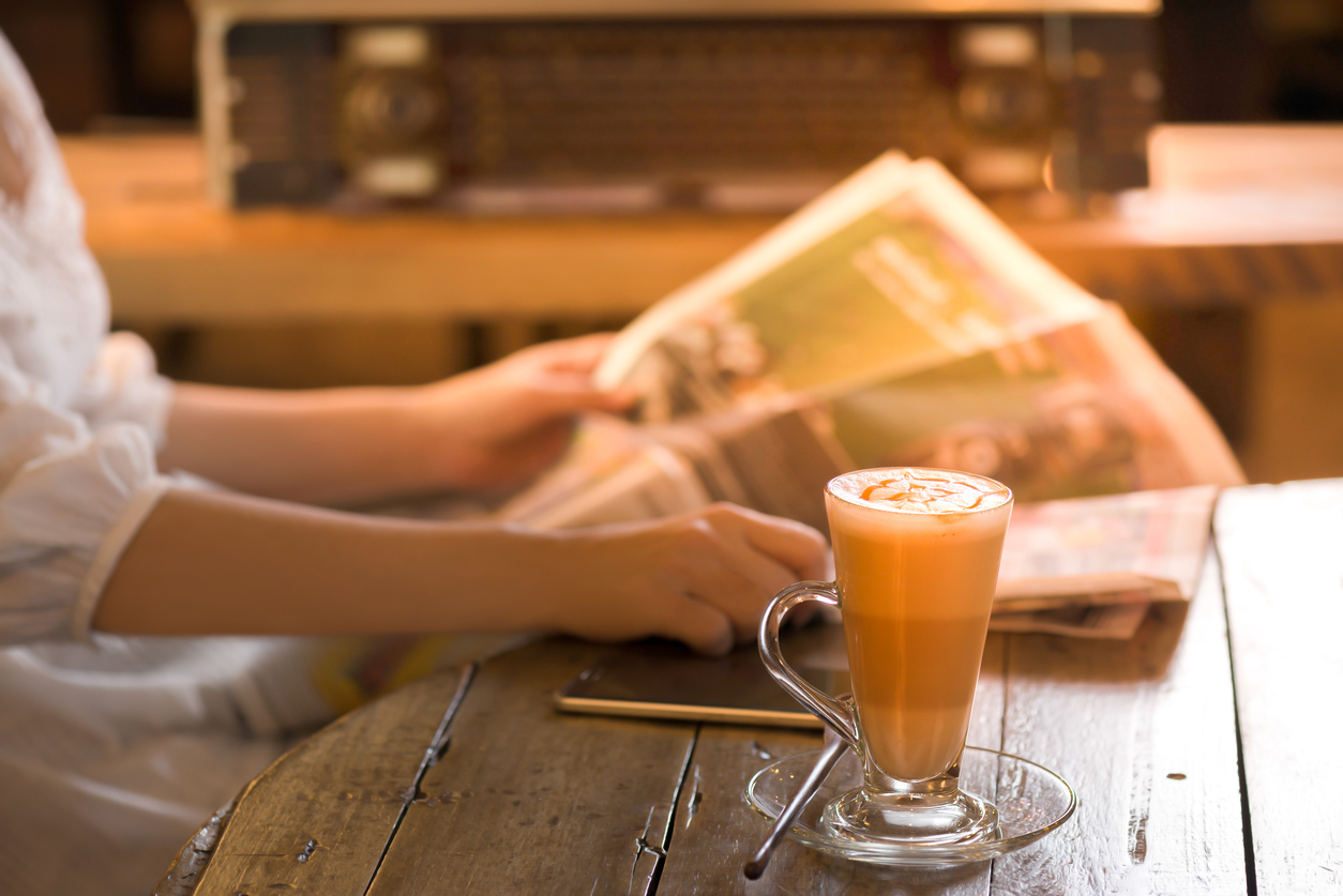 Woman reading newspaper with a cup of coffee Start a new day with fresh tasty coffee and newspaper in vintage coffee shop