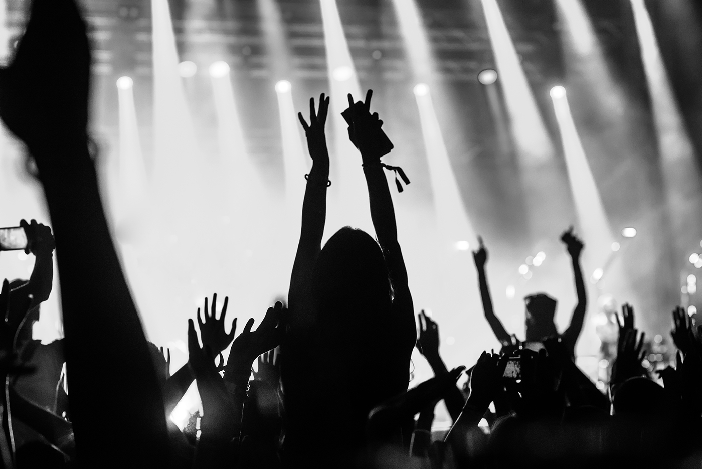 Black and white photo of a girl raising hands while enjoying good music.