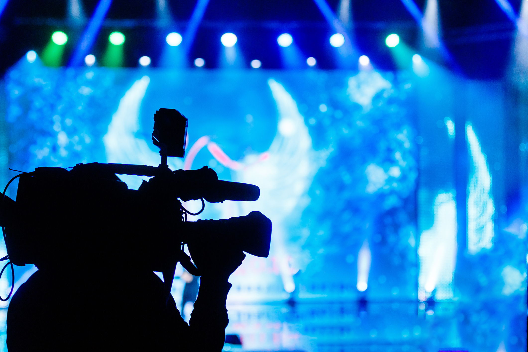 Professional Video camera operator working with his equipment, blue background Professional Video camera operator working with his equipment, blue background