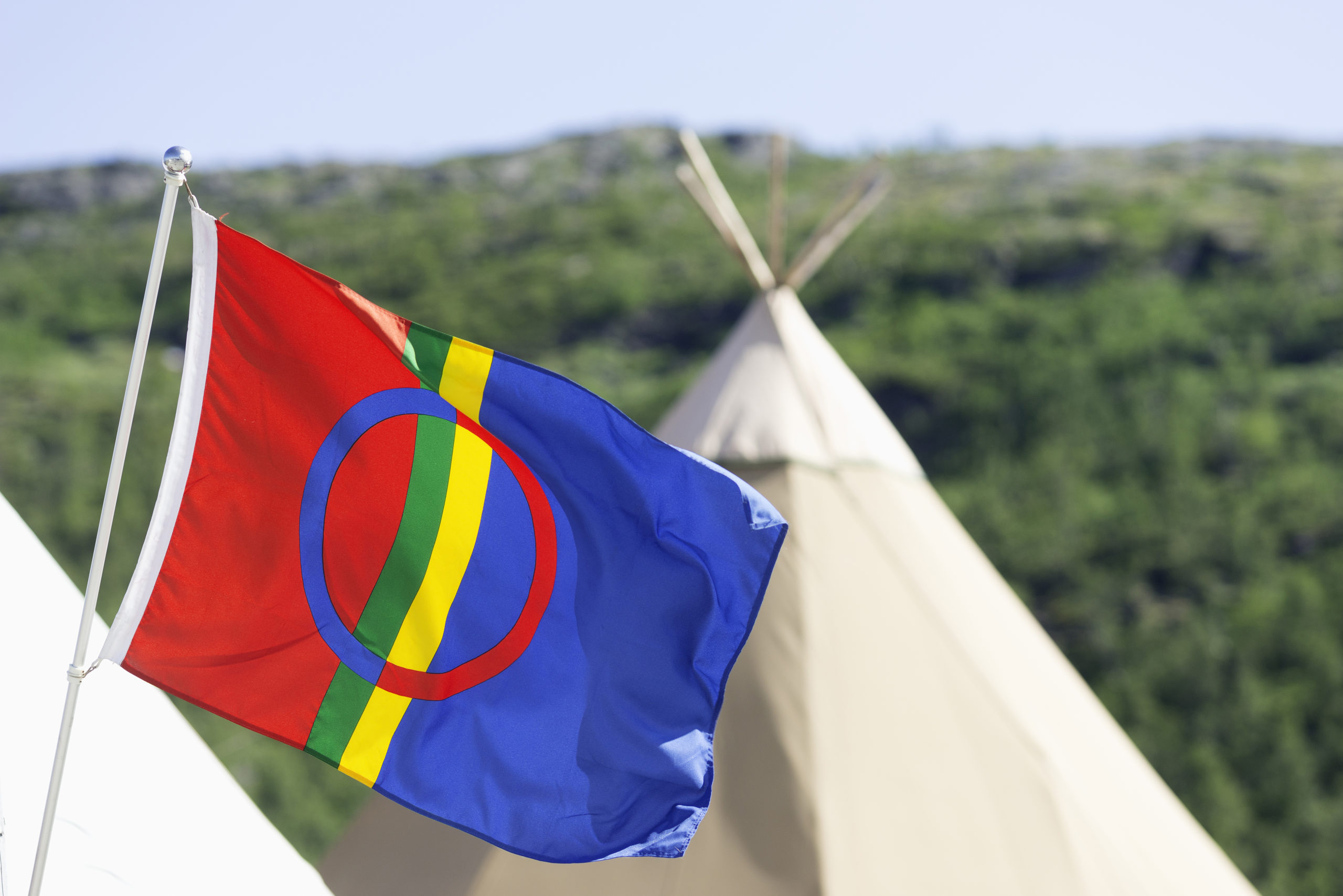 IVVoSnKPV1o Sameflagg som vaier i vinden. Lavvo i bakgrunnen.